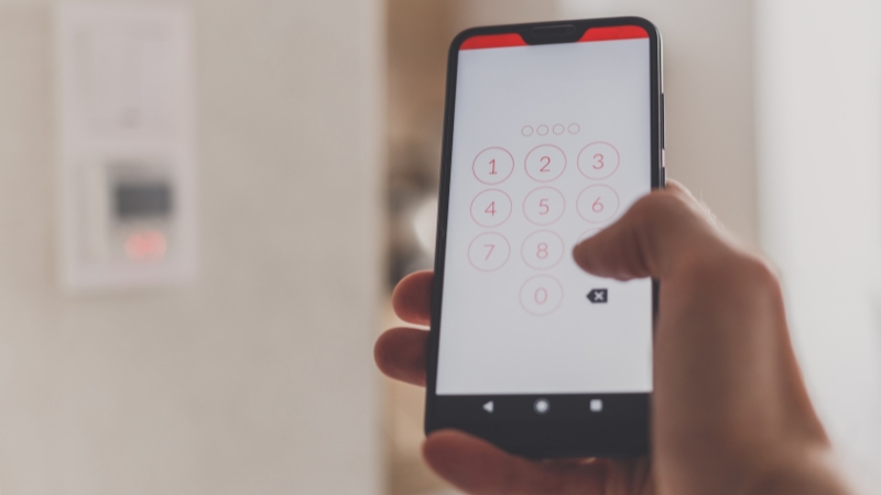 Osoba unosi šifru na telefonu za upravljanje alarmom